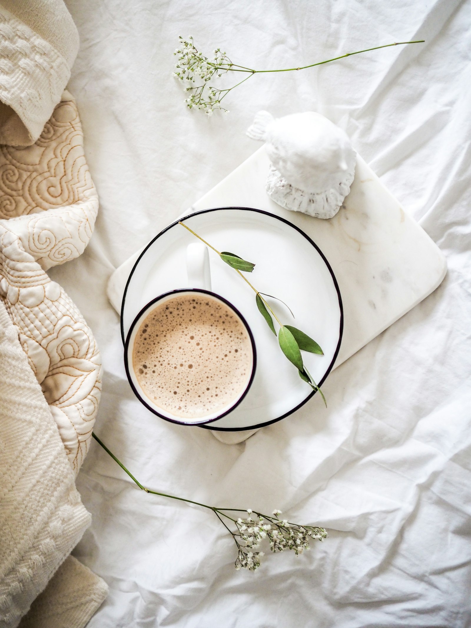 Tasse de café sur du linge blanc et des fleurs : un accompagnement bienveillant avec une napsothérapeute à Lyon.